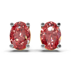 A pair of oval-cut red gemstone stud earrings in four-prong settings with gold and silver metal borders, shown on a clean white background.