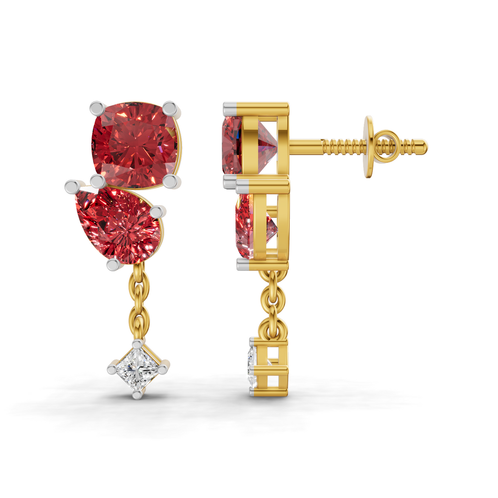 A pair of gold and white gold drop earrings with red gemstones, shown on a clean white background. One earring is shown from the front, displaying a cushion-cut red gemstone, a teardrop-shaped red gemstone, and a dangling clear gemstone.