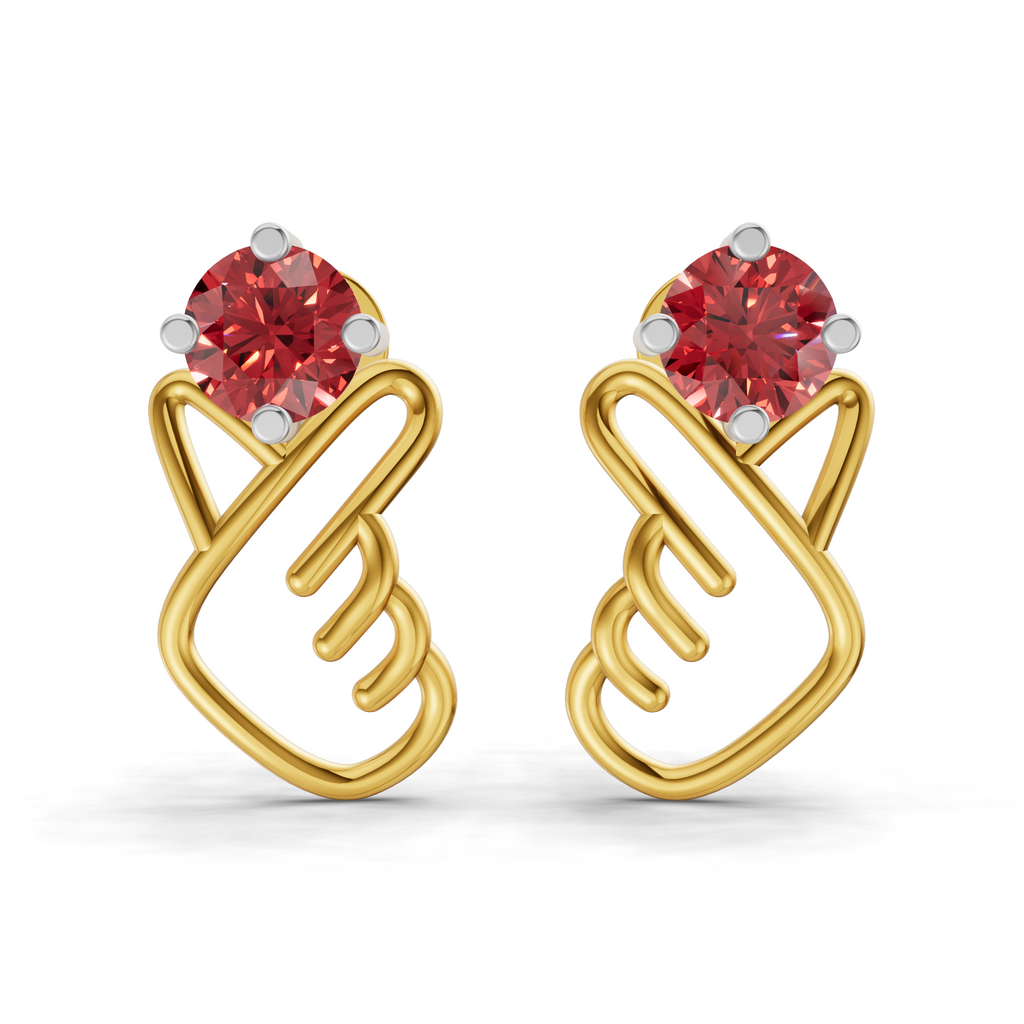 A pair of gold earrings with a stylized heart design, featuring a round red gemstone at the top of each heart and small silver prongs, shown on a clean white background.