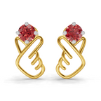 A pair of gold earrings with a stylized heart design, featuring a round red gemstone at the top of each heart and small silver prongs, shown on a clean white background.